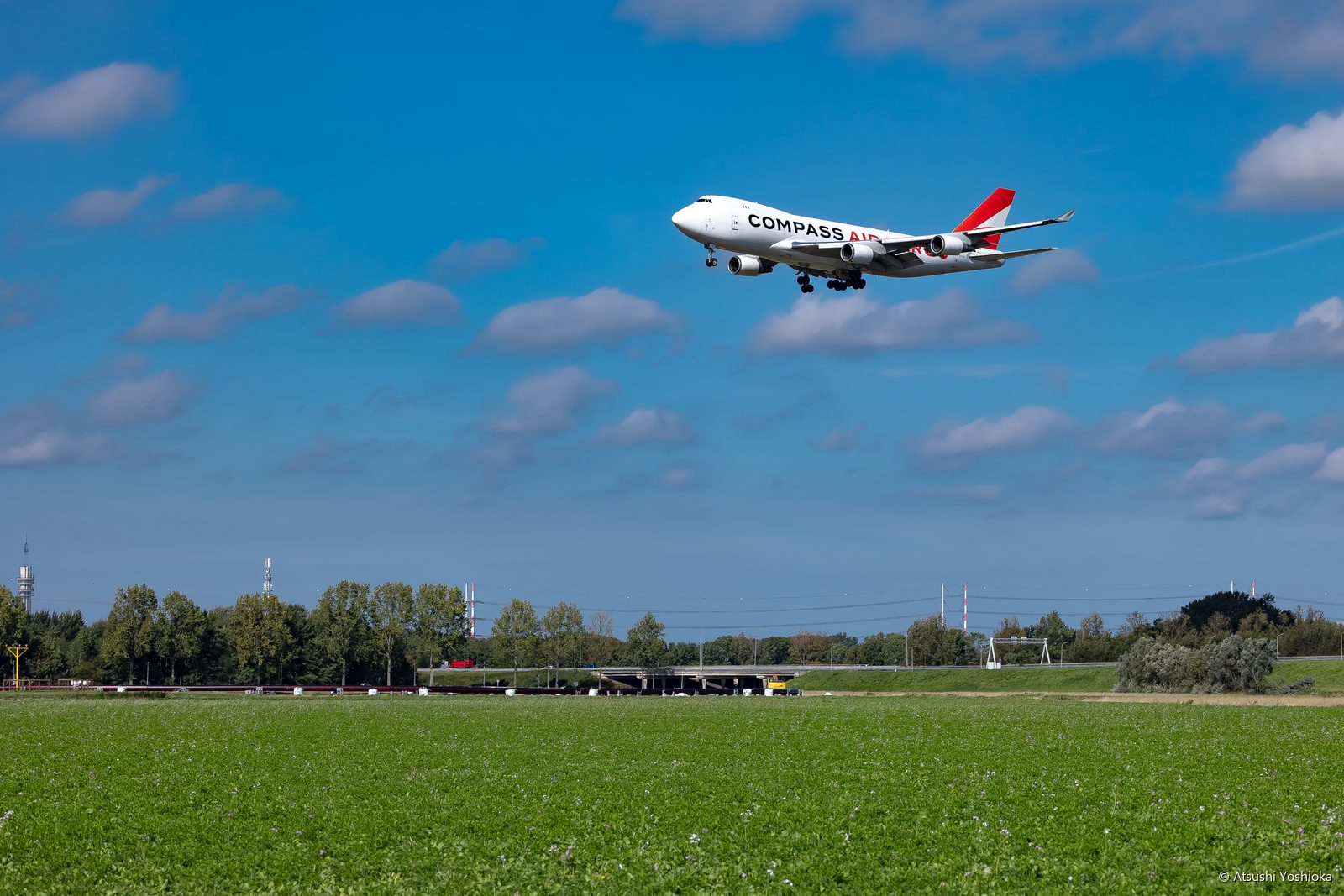 青空と雲の中を着陸に向かうコンパス・カーゴのボーイング747