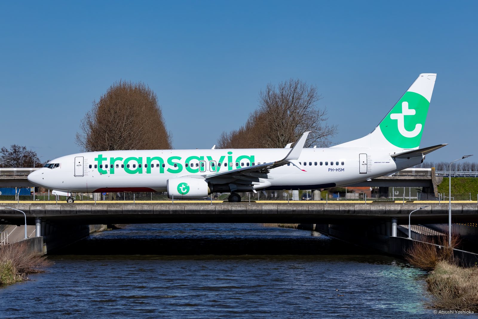運河に架かる誘導路の橋を渡るトランサヴィアのボーイング737