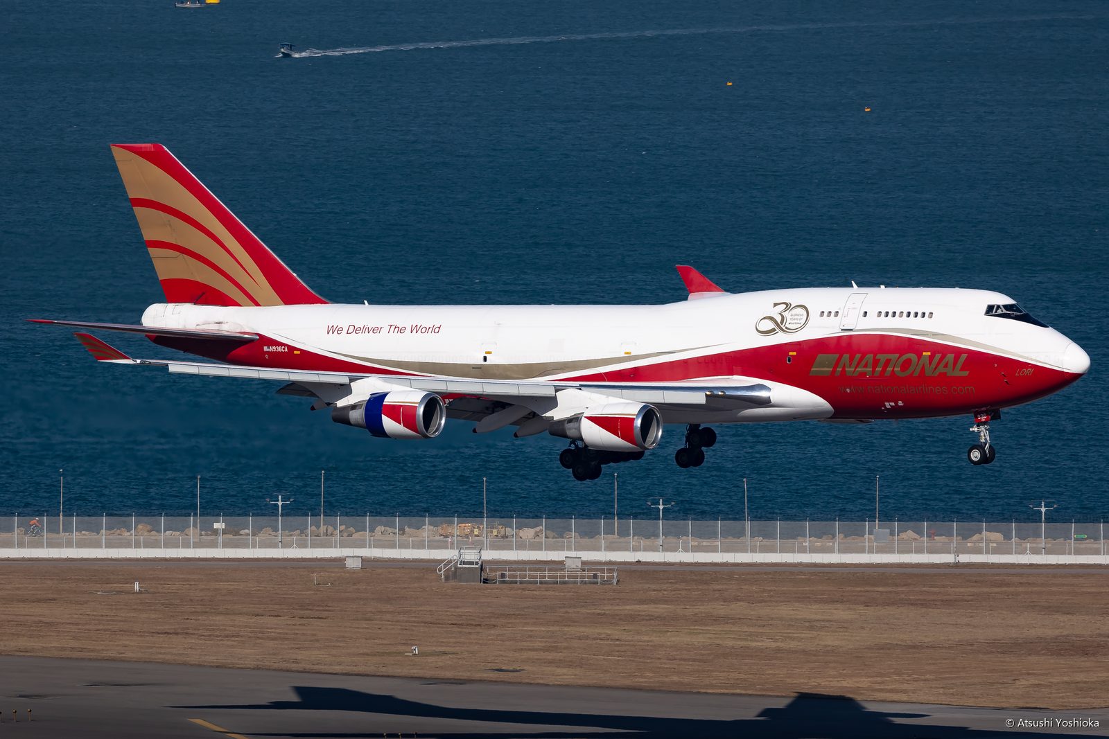 海の上を飛ぶ赤い塗装のナショナル航空ボーイング747