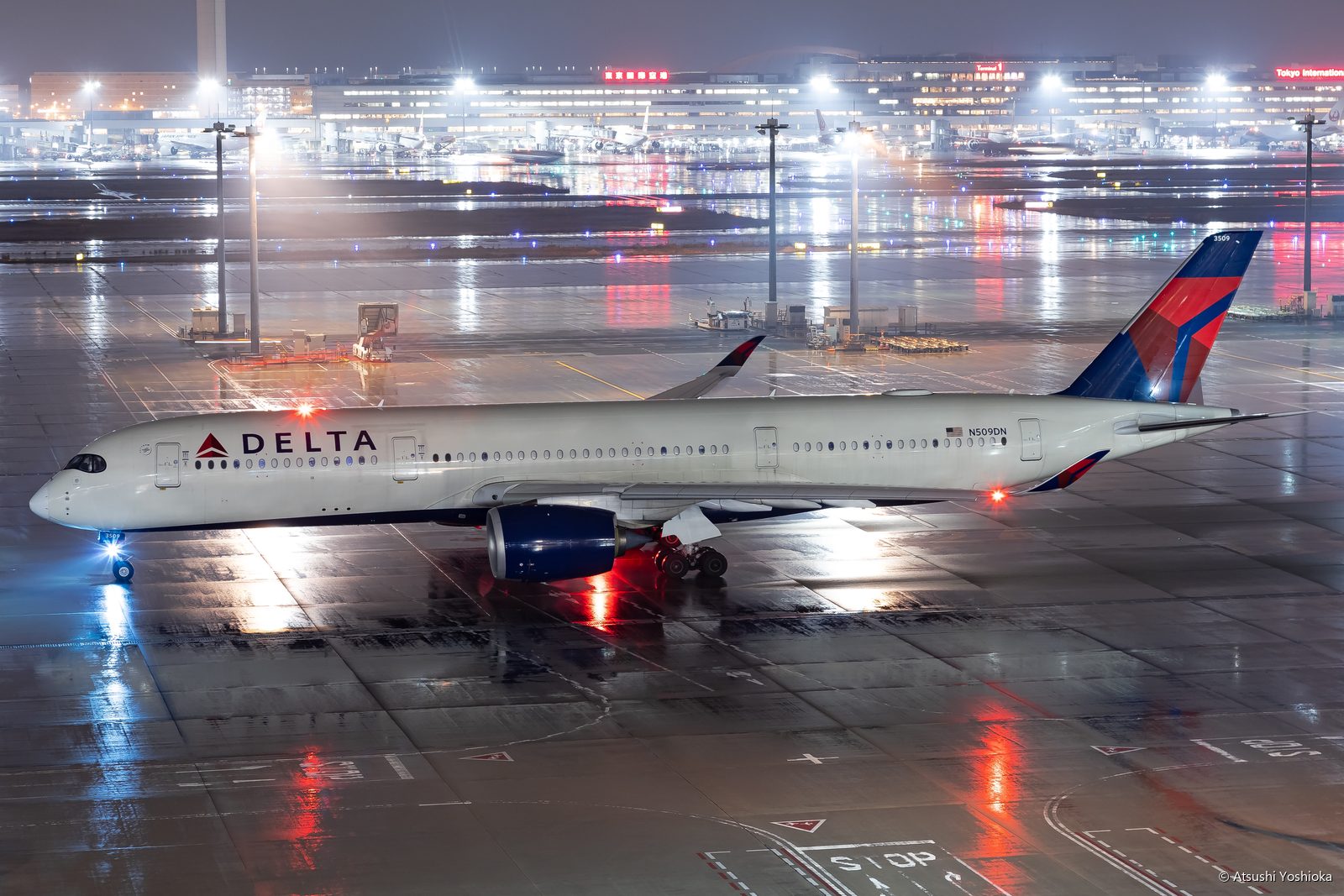 雨に濡れた夜の駐機場に停まるデルタ航空のエアバスA350