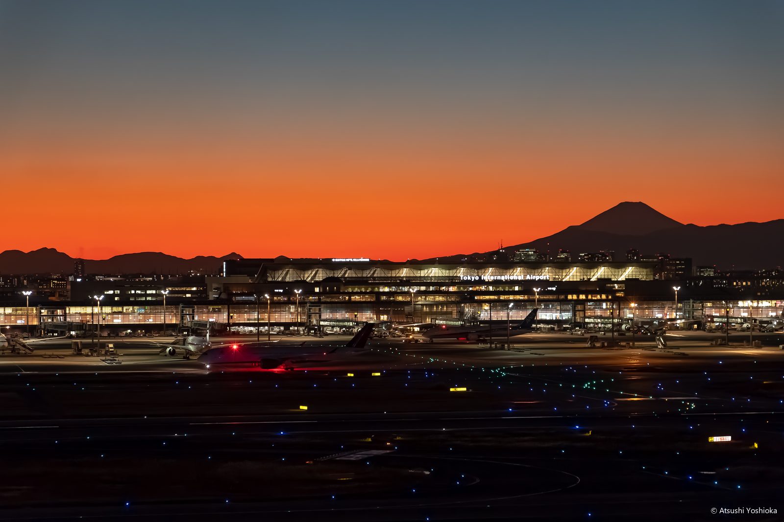 夕焼けの空に富士山のシルエットと羽田空港の明かり